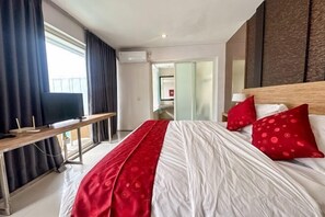 A hotel room with a large bed, a desk, and a television.