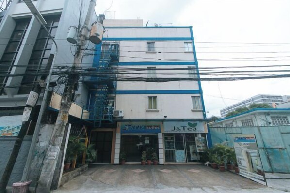 A building with a J&Tea sign, multiple floors, and a staircase. - J and T Jamich Suites by RedDoorz (Pasay)