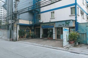 A building with a blue and white facade, a sign for 'J&Tea,' and a sign for 'AMICH Suites.' - J and T Jamich Suites by RedDoorz (Pasay)