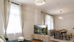 A modern living room with a TV, sofa, dining table, chairs, and a view of a lake. - Ruhestein - Quartier characterful flat,  122m², near the railway station & Iven (Baiersbronn)
