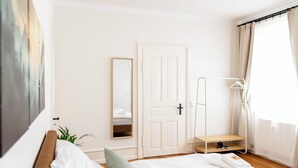 A bedroom with a bed, a wardrobe, a mirror, a hanging rack, and a window with curtains. - Ruhestein - Quartier characterful flat,  122m², near the railway station & Iven (Baiersbronn)