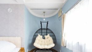 Una habitación con una cama, una silla colgante, una lámpara en el techo y una ventana con cortinas.