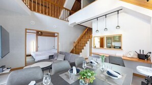 Una habitación de hotel moderna con comedor, una escalera y vistas a la cocina.
