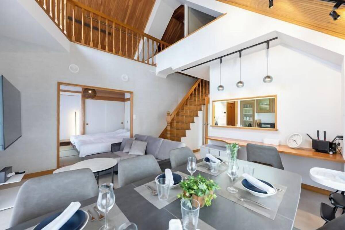 Una habitación de hotel moderna con comedor, una escalera y vistas a la cocina.