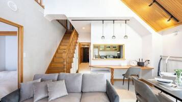 A modern interior with a sofa, dining table, and kitchen area.