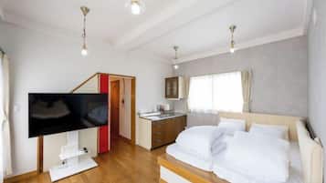 A bedroom with a bed, a TV, a desk, and a window.