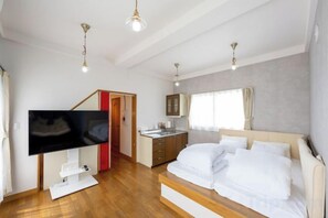 Une chambre à coucher avec un lit, une télévision, un bureau et une fenêtre.