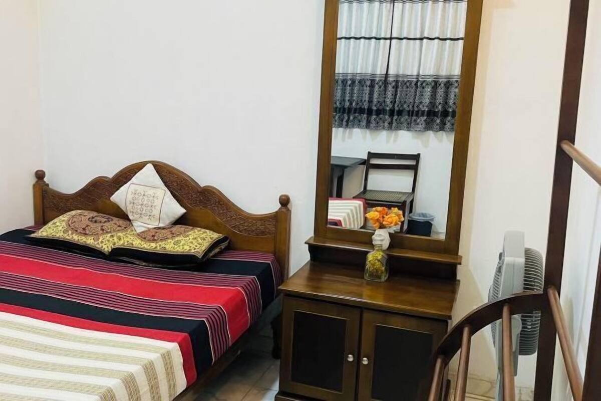 Une chambre à coucher avec un lit en bois, une table de chevet avec un miroir et une petite armoire.