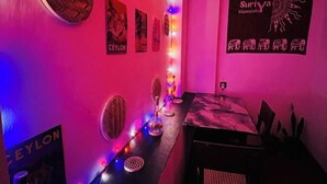 A room with a long table, wall-mounted lights, and posters. - Suriya Haven Homestay (Badulla)