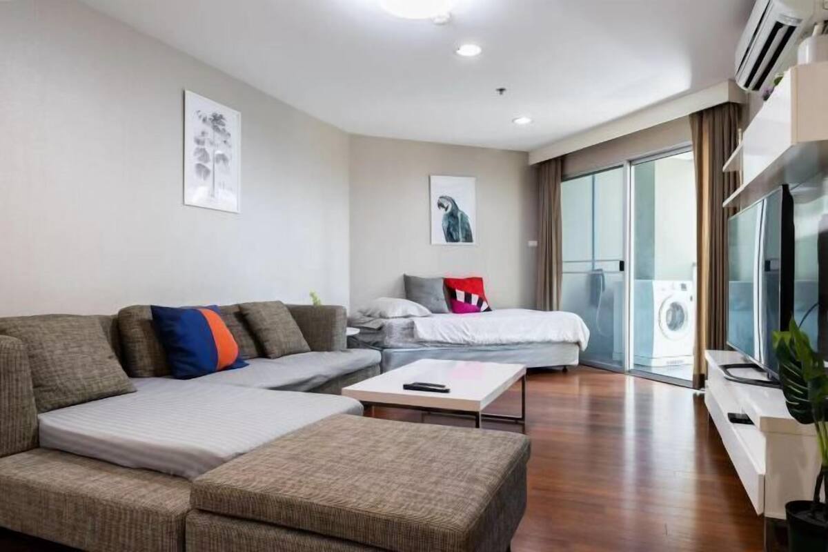 Uma sala de estar moderna com um sofá, uma cama, uma mesa de centro e uma televisão.