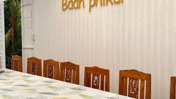 A dining area with a table and chairs, a wall with text, and a partial view of a plant.