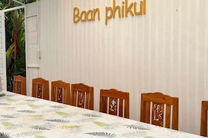 Un espace repas avec une table et des chaises, un mur orné de texte et une vue partielle sur une plante.