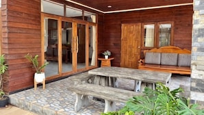 A wooden exterior with a patio area, a sliding glass door, a wooden bench, and a sofa. - Pikul Homestay (Hat Yai)