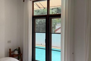 Ein Zimmer mit einem großen Schiebeglasfenster, das zu einem Poolbereich führt.