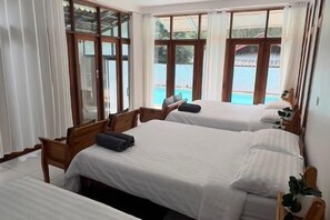 Une chambre d’hôtel avec deux lits, une chaise en bois, une petite table et une vue sur une piscine.