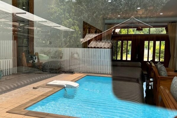 Une piscine avec un jacuzzi, un bain de soleil et une vue sur l’extérieur.