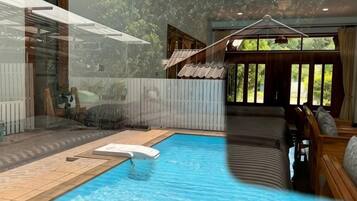 A swimming pool with a sun lounger, a wooden deck, and a view of the outdoors.