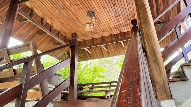 A wooden staircase leading to a covered area with a wooden ceiling and a hanging light fixture. - Pikul Homestay (Hat Yai)