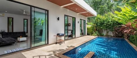 A modern house with a swimming pool, glass doors, and outdoor furniture.