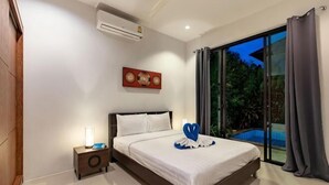 Een slaapkamer met een bed, nachtkastje, airconditioning, schilderij en uitzicht op een zwembad.