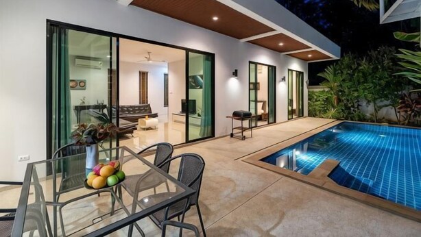 Een modern huis met een glazen eettafel, een zwembad en een patio.