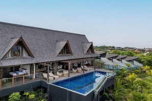 A modern villa with a glass infinity pool, wooden deck, and a view of the surrounding greenery. - Khaya Luxury Villas (Bali)