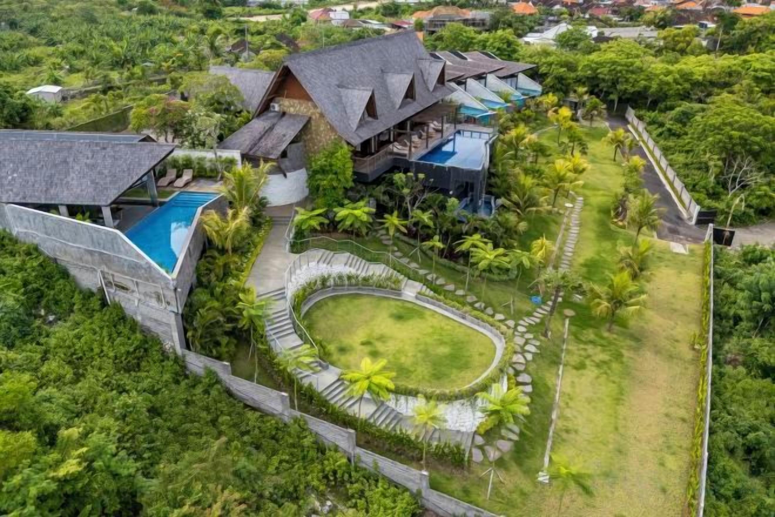 A large resort with multiple buildings, a swimming pool, and lush greenery.