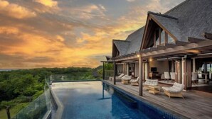 A modern villa with a large infinity pool, outdoor seating, and a scenic view. - Khaya Luxury Villas (Bali)