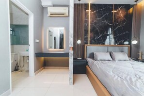 A modern bedroom with a bed, bedside table, and a marble-patterned wall. - Twin Galaxy Residences (Johor Bahru)