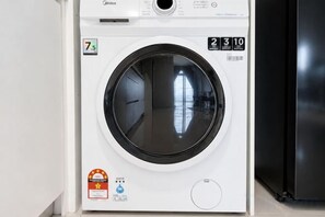 A front-loading washing machine with a digital display, a control panel, and a water level indicator. - Twin Galaxy Residences (Johor Bahru)