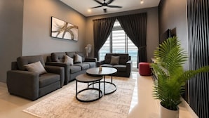 A modern living room with a sofa set, a coffee table, a ceiling fan, and a large window with curtains. - Twin Galaxy Residences (Johor Bahru)