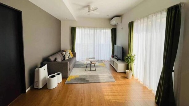 Ein modernes Wohnzimmer mit Sofa, Fernseher und Deckenventilator.