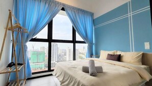 A hotel room with a large window, a bed with a rolled towel, a wooden ladder, and a city view. - Skyblue 2 Rooms Apartment, 4+2 Pax @ Urban Suites (George Town)