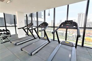 A gym with treadmills and dumbbells, large windows, and a city view. - Skyblue 2 Rooms Apartment, 4+2 Pax @ Urban Suites (George Town)