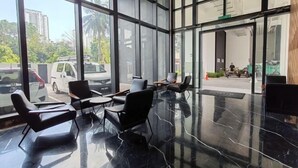 A spacious lobby with large windows, black chairs, and a polished marble floor. - Skyblue 2 Rooms Apartment, 4+2 Pax @ Urban Suites (George Town)