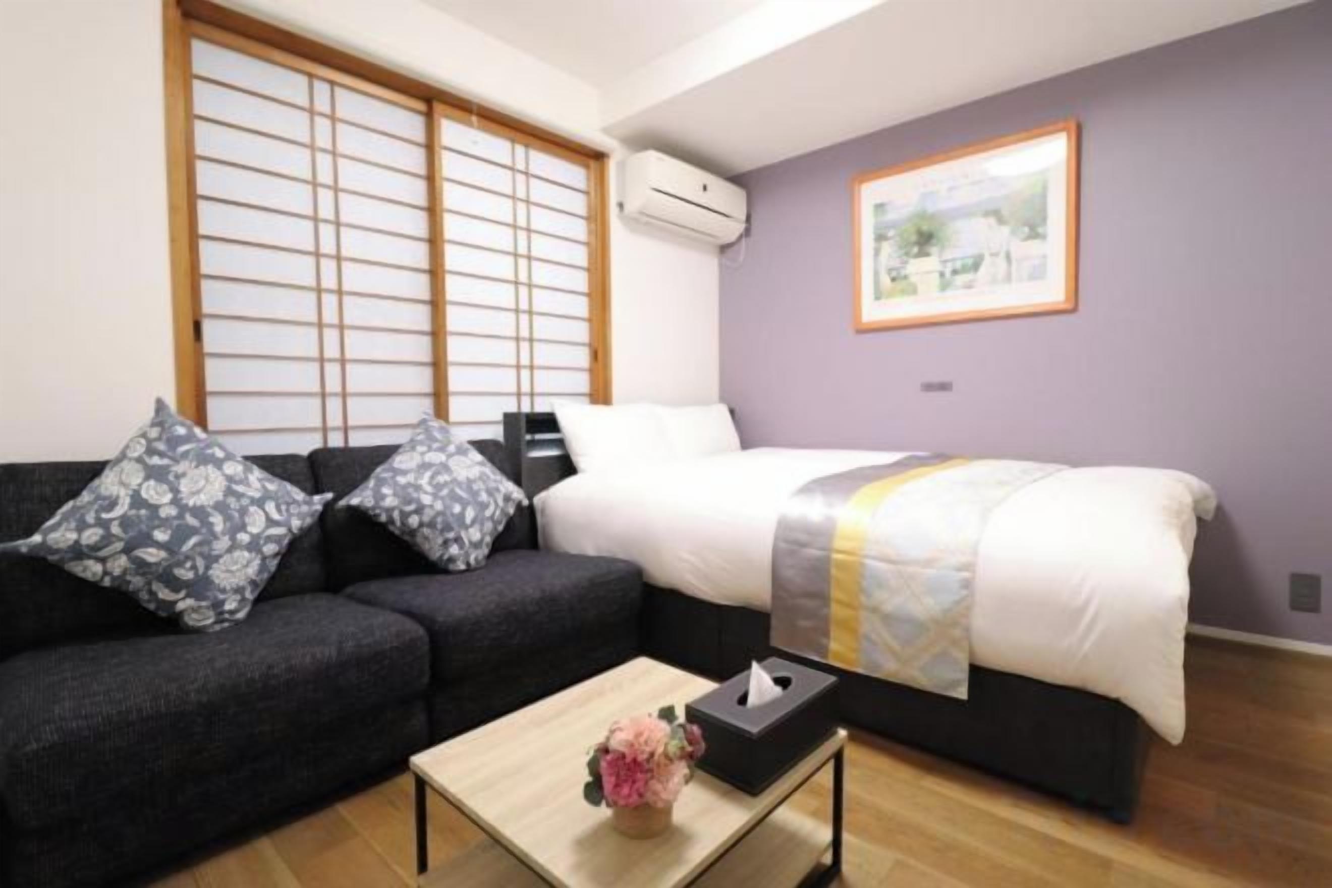 A room with a bed, a sofa, a coffee table, and a picture on the wall.