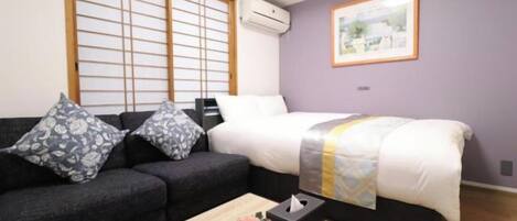 A room with a bed, a sofa, a coffee table, and a picture on the wall.