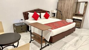 A hotel room with a large bed, bedside tables, a desk, and a wardrobe.