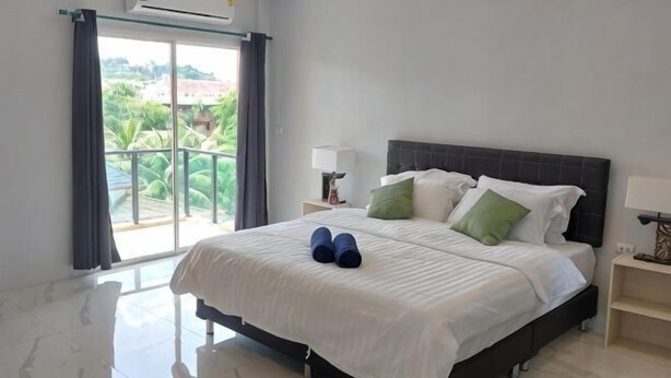 A bedroom with a bed, a nightstand, a lamp, and a view through a sliding door.