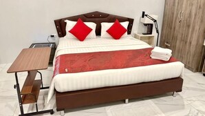 A neatly made bed with a headboard, a bedside table, a lamp, and a wardrobe in a hotel room.