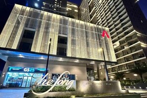 Un edificio moderno con un llamativo logo en forma de 'A', una entrada visible con el rótulo 'GS25' y un letrero con el texto 'hejong'.