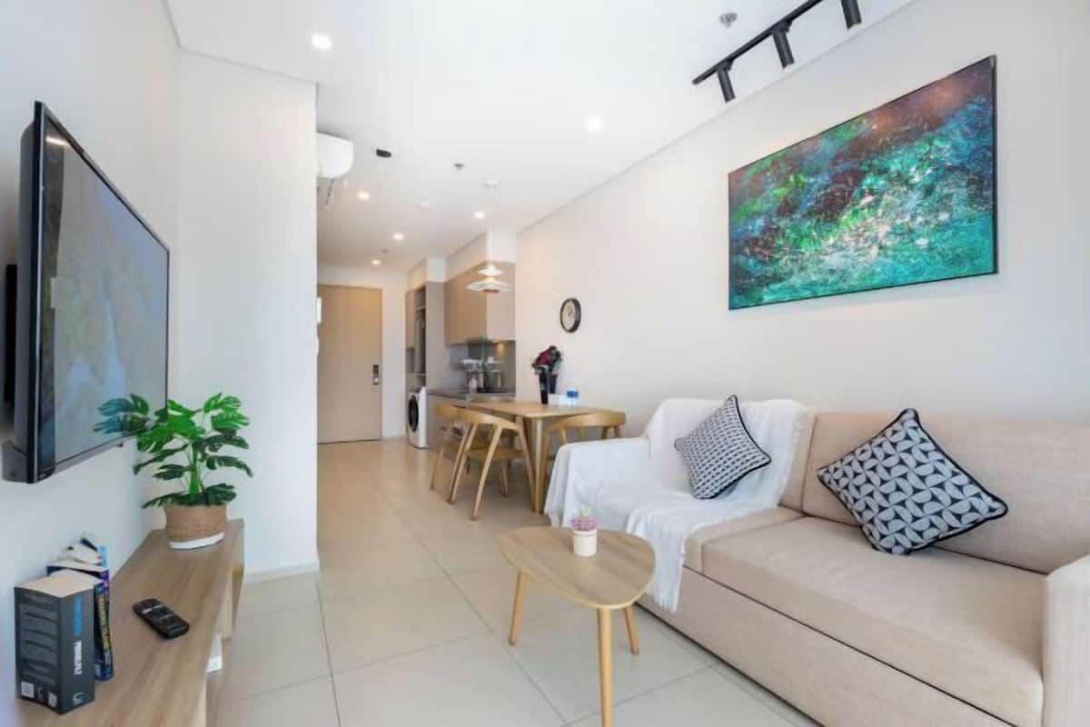 A modern living room with a sofa, coffee table, TV, and artwork.