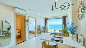 A modern dining area with a view of the sea, a dining table set for four, and a large decorative clock on the wall. - The Song Vung Tau - Hong Hanh Apartments (Vung Tau)