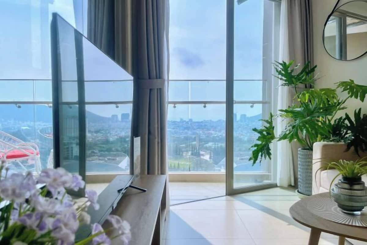 A modern room with a large window, a wooden table, and potted plants.