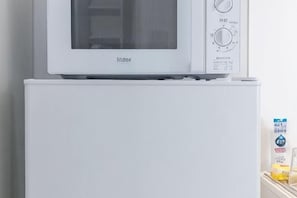 A microwave oven on top of a white refrigerator.
