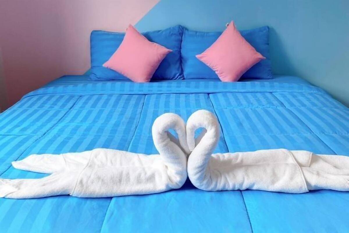 Een bed met blauw beddengoed en twee roze kussens.