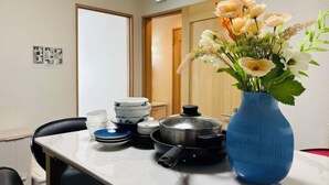 A room with a table set with plates, bowls, and a pot. There is a blue vase with flowers on the table. - Lapis House 201 2F&3F (Tokyo)