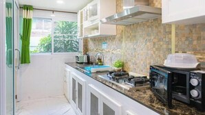 A compact kitchen with a microwave, toaster, and small sink. - Friend House BKK (Bangkok)