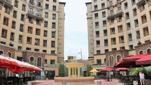 Une cour avec des sièges en plein air, une fontaine centrale et, en arrière-plan, des immeubles de grande hauteur.