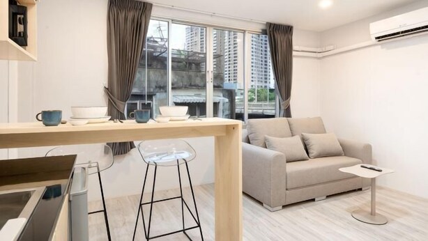 A modern living room with a sofa, a small table, a TV, and a window with curtains.